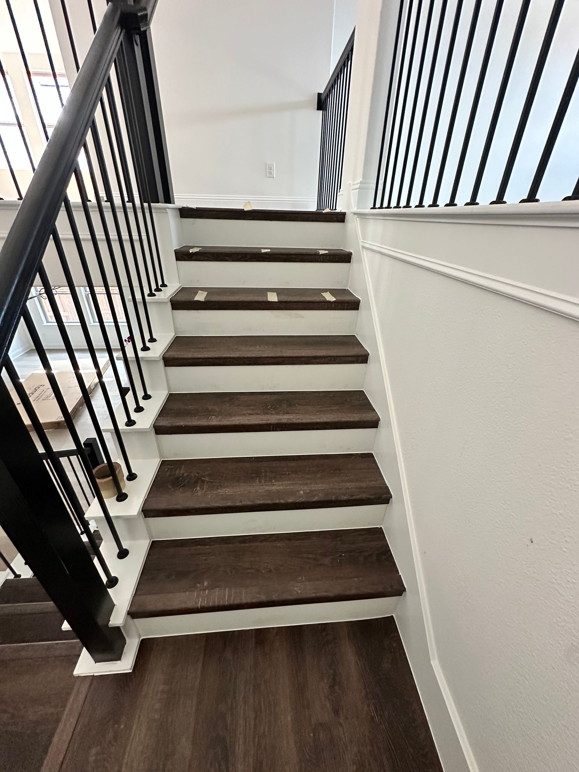 Staircase with dark wooden steps, white risers, and a black railing, leading upwards.