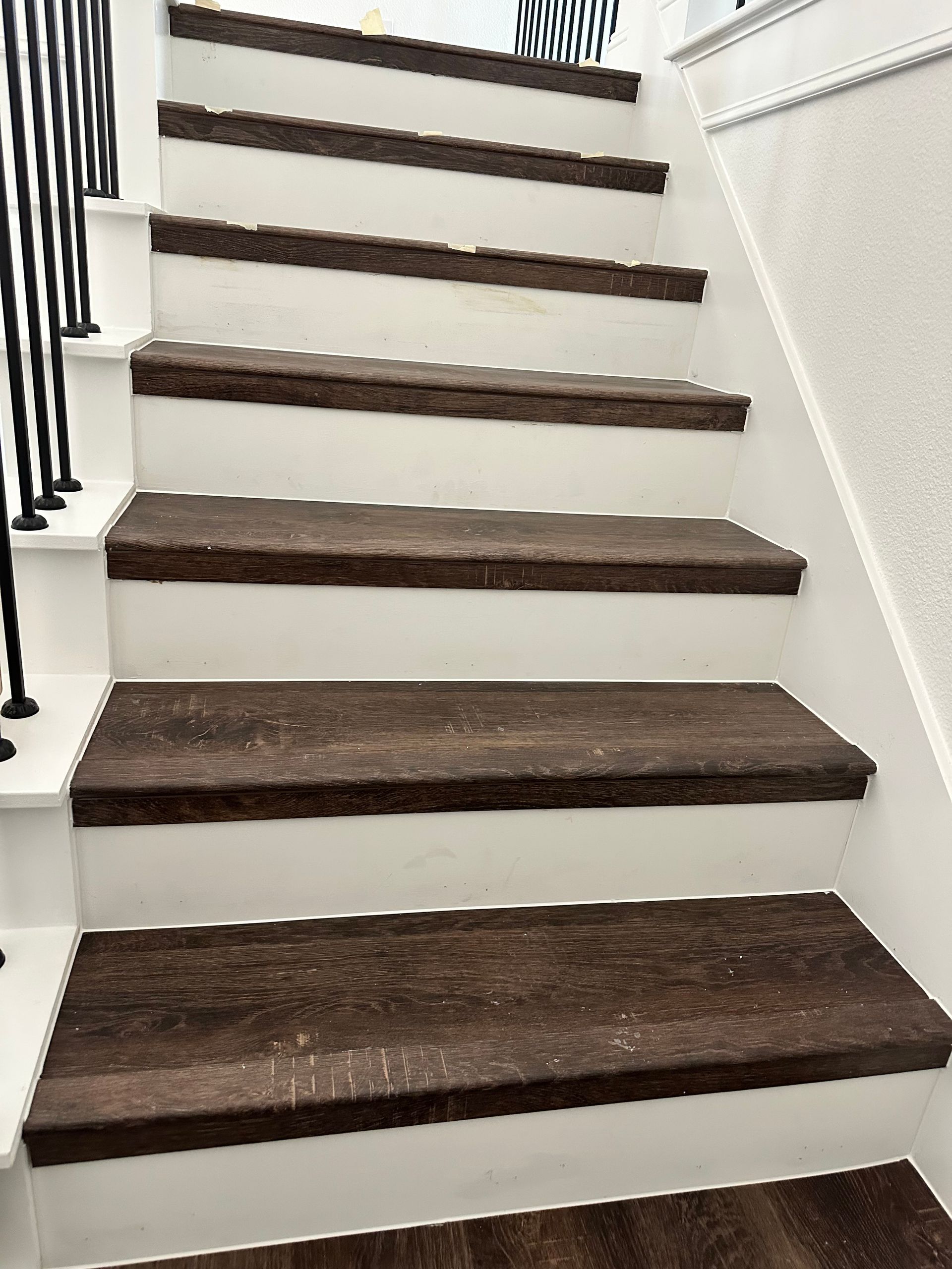 Staircase with brown carpet steps and white risers. Black railing on one side.