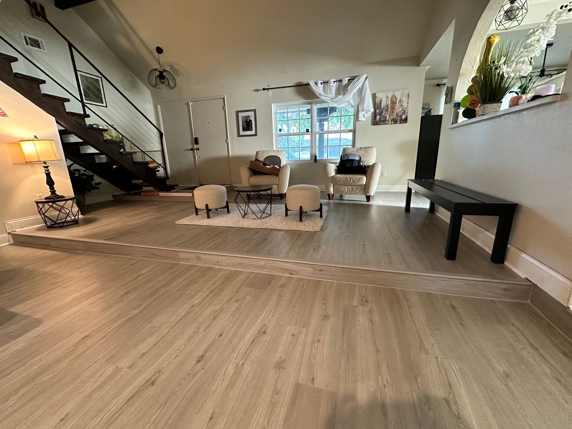 Living room with neutral floors, seating area, stairs, and black bench.