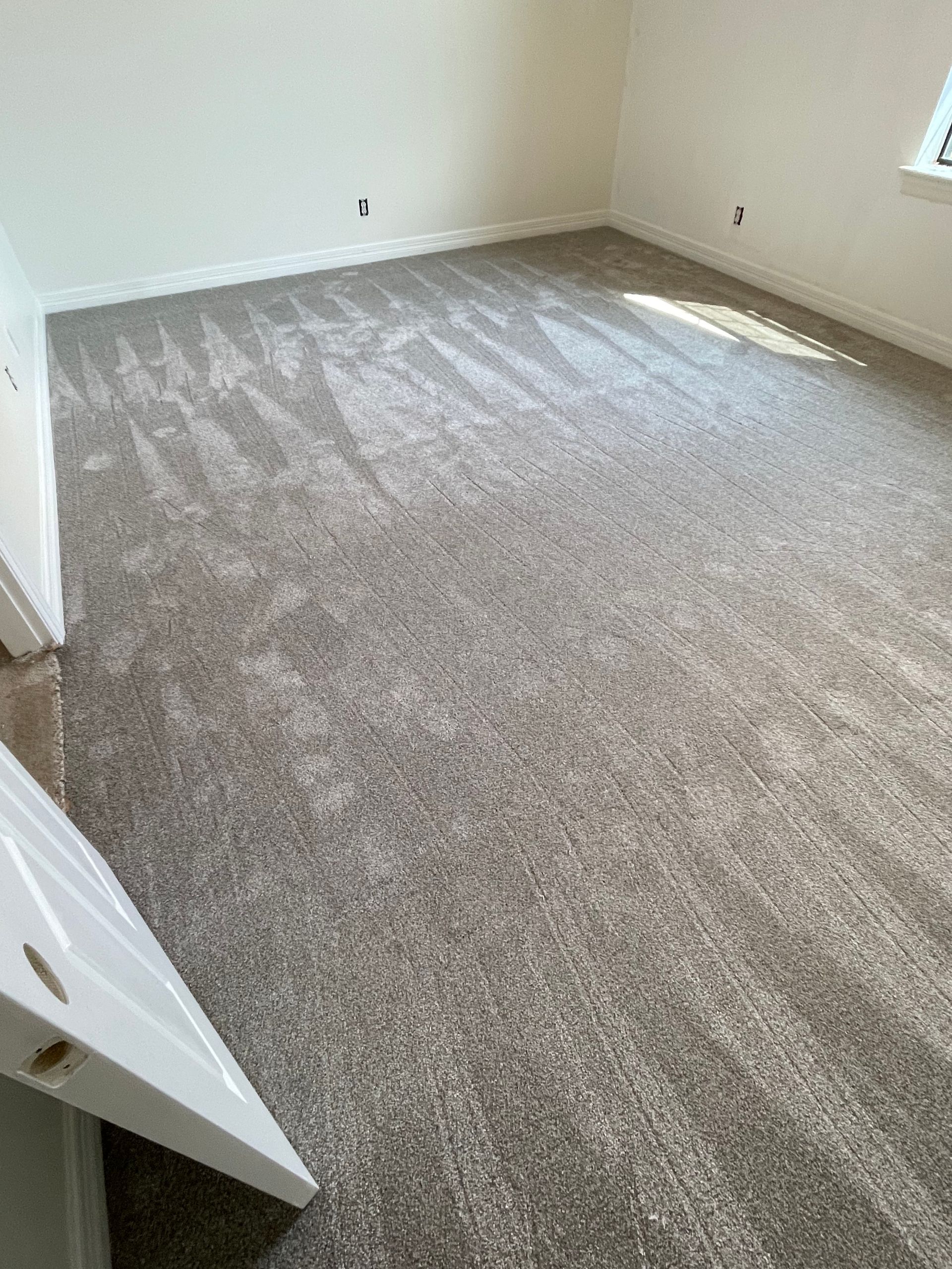 Gray carpeted room with white walls, possibly recently installed.