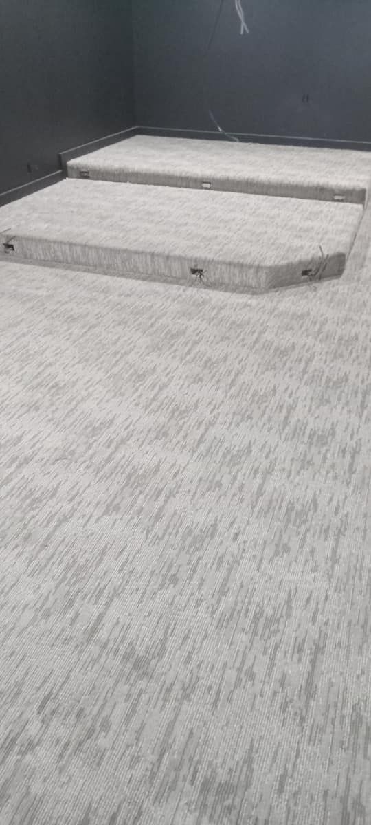 Gray carpeted tiered platform in a dark room.