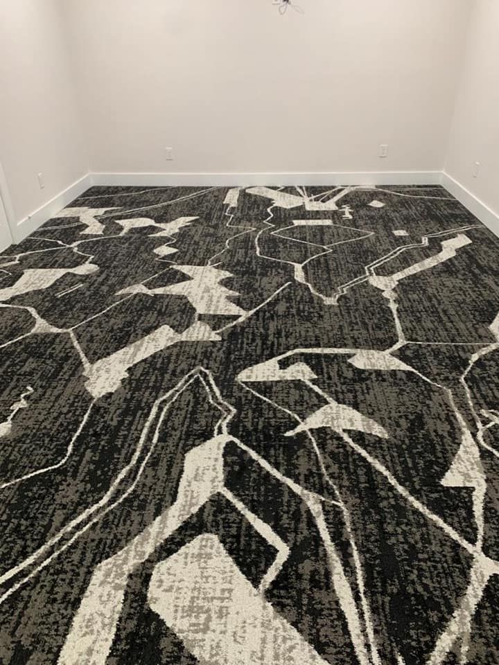 Room with patterned carpet in black, white, and gray; white walls and baseboards.