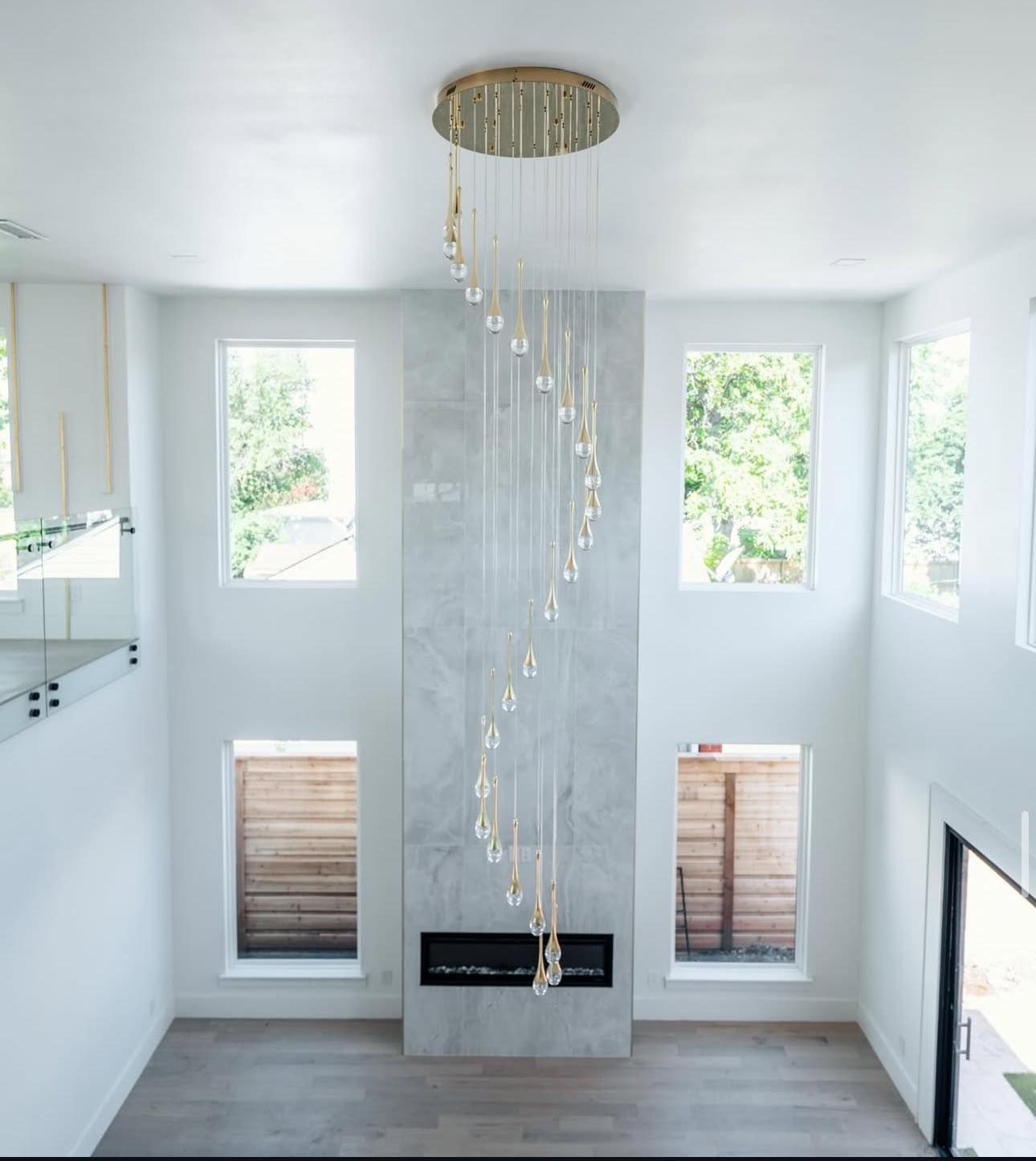 Modern living room with a fireplace, windows, and a spiral crystal chandelier.