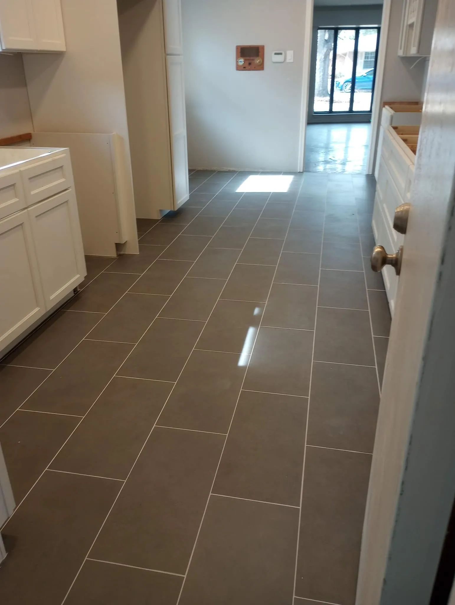 Kitchen with dark gray tile floor, white cabinets, and doorway leading to a hallway.