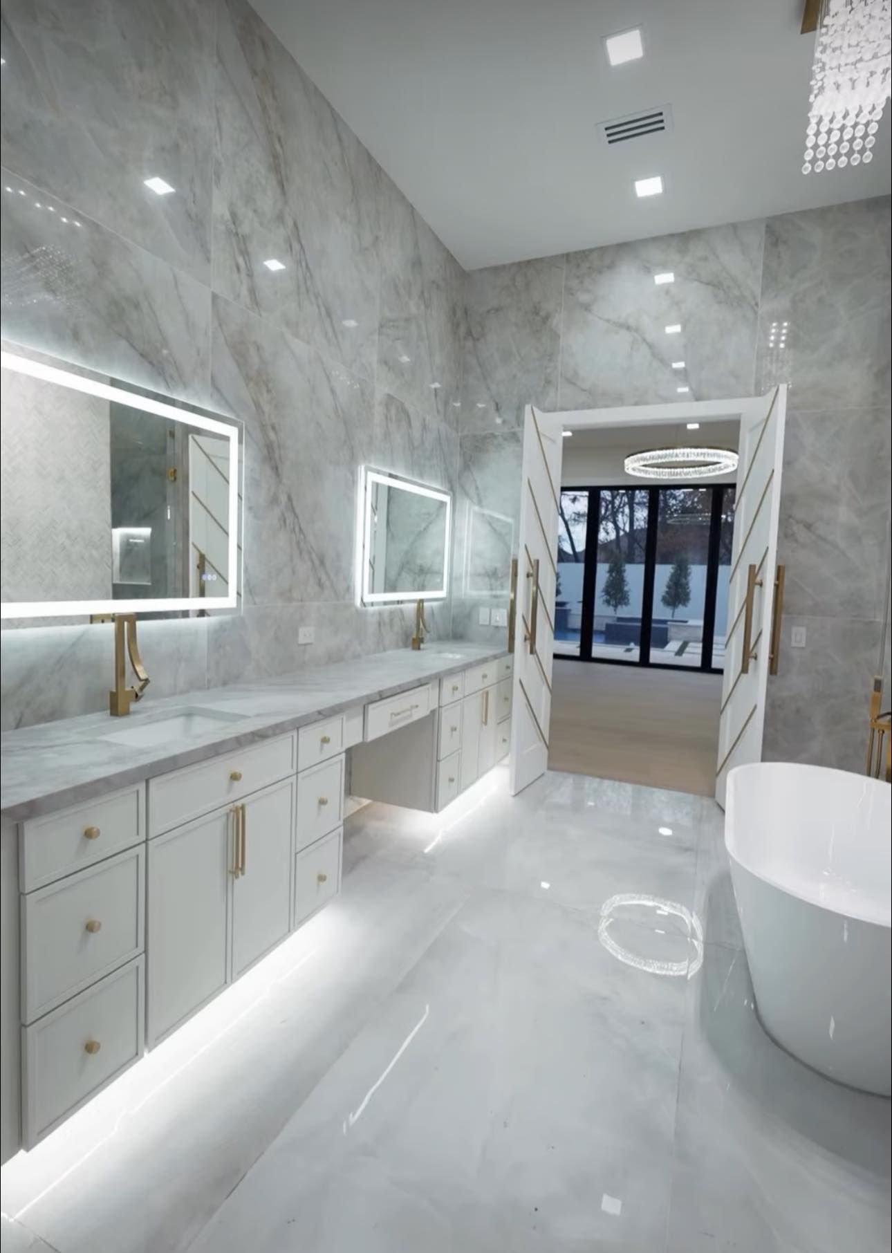 Luxurious, modern bathroom with marble walls, double vanity, and freestanding tub.
