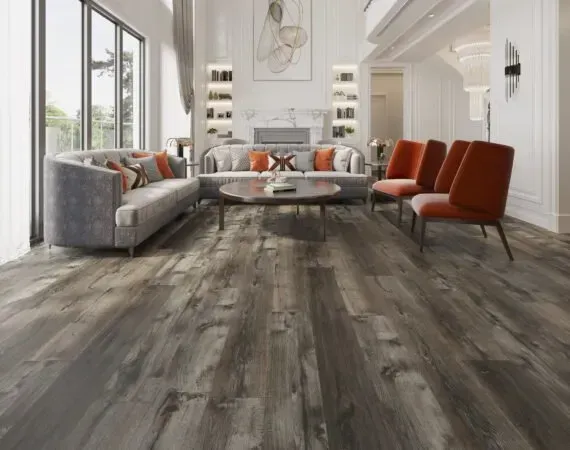 Living room with gray wood flooring, velvet sofa, orange chairs, and a fireplace.