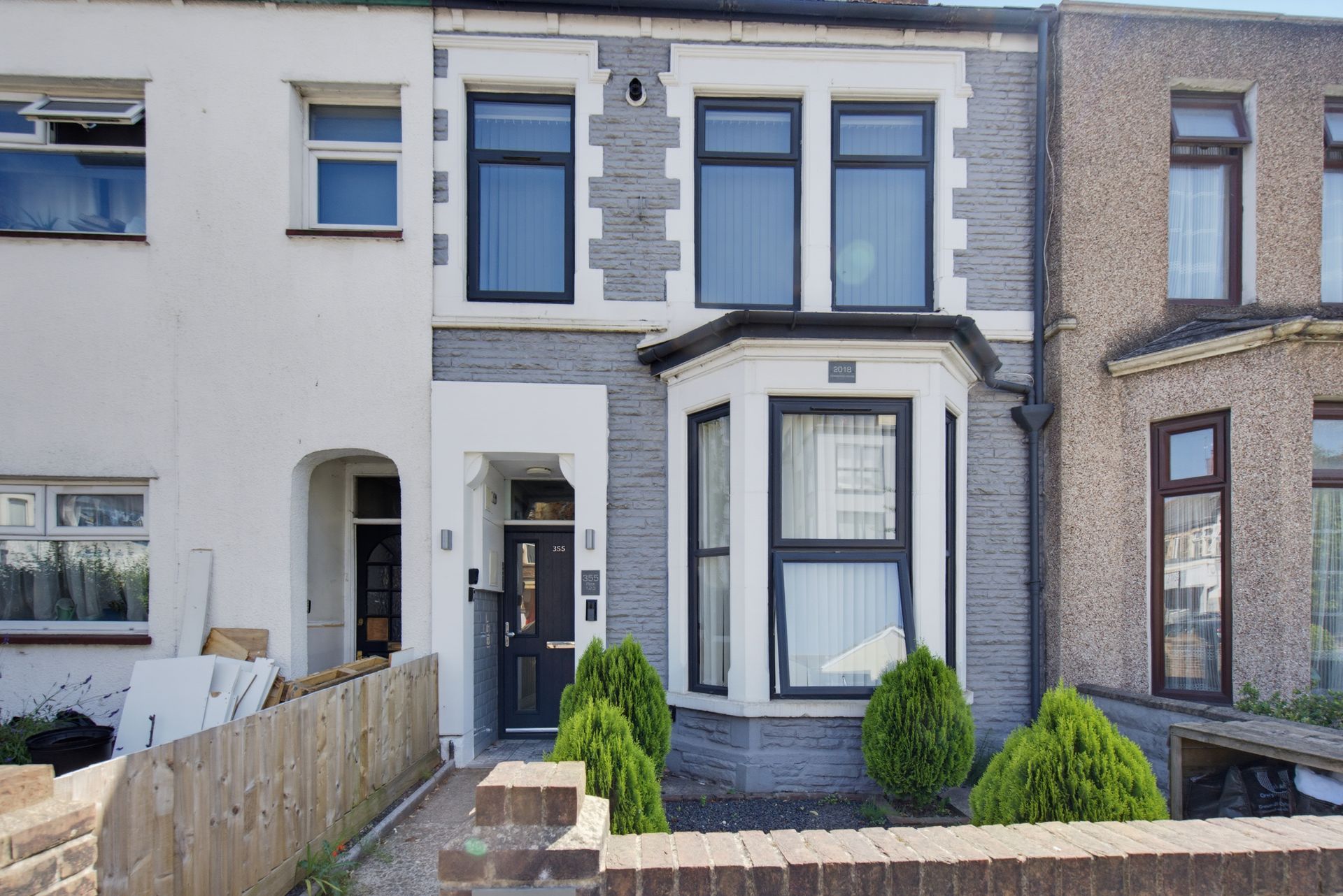 Row of terraced houses with gray and white facades, front doors, and small front gardens