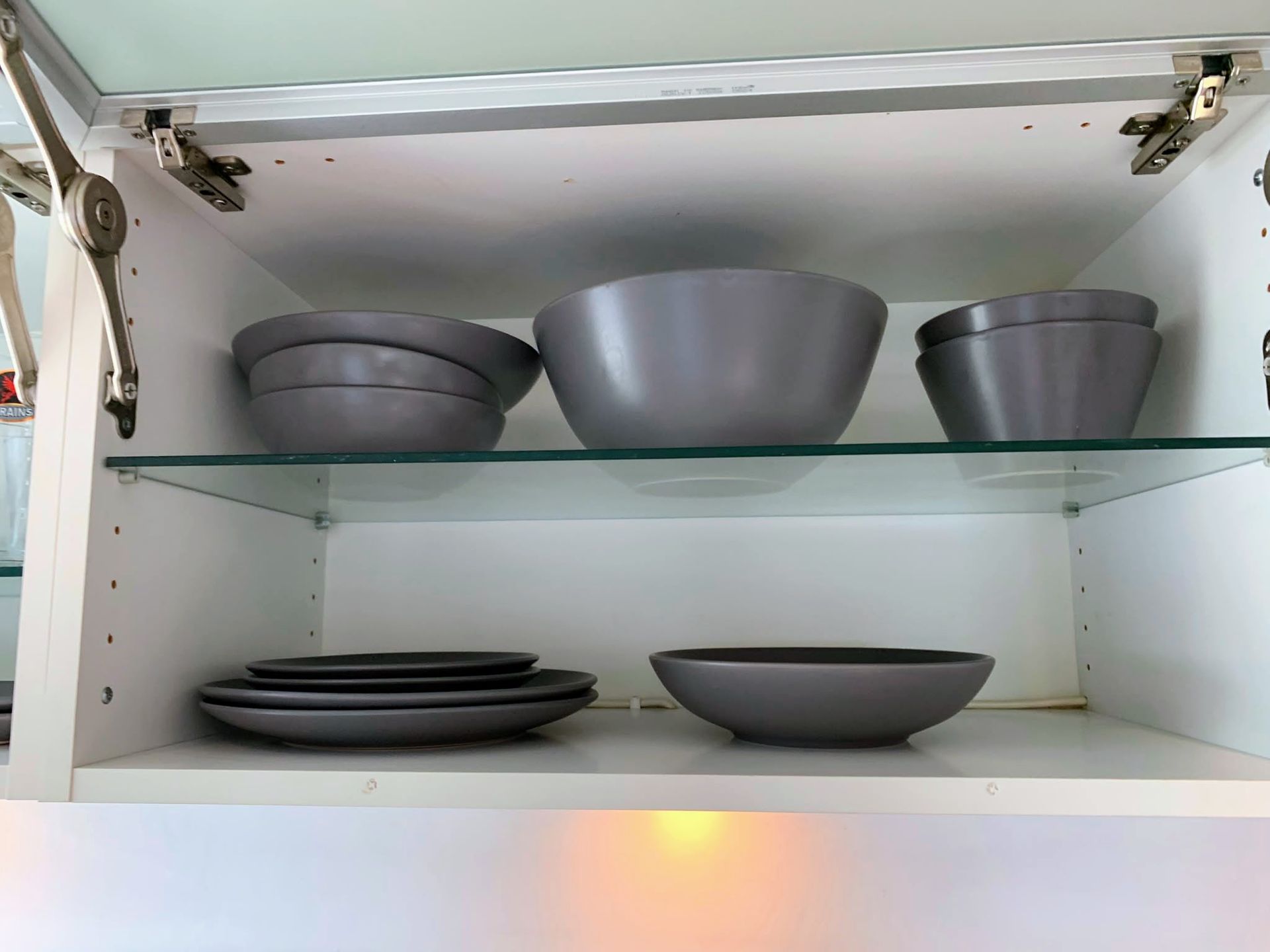 Glass cabinet with gray bowls and plates on two shelves