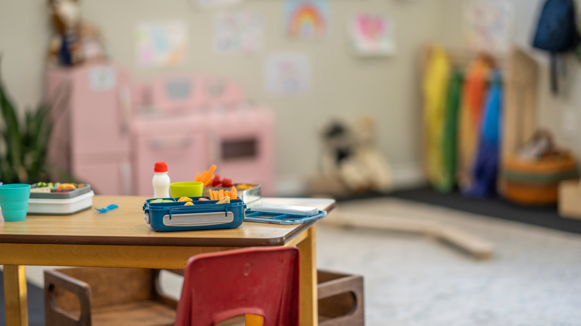 A wooden table and chairs in a classroom with toys on it.