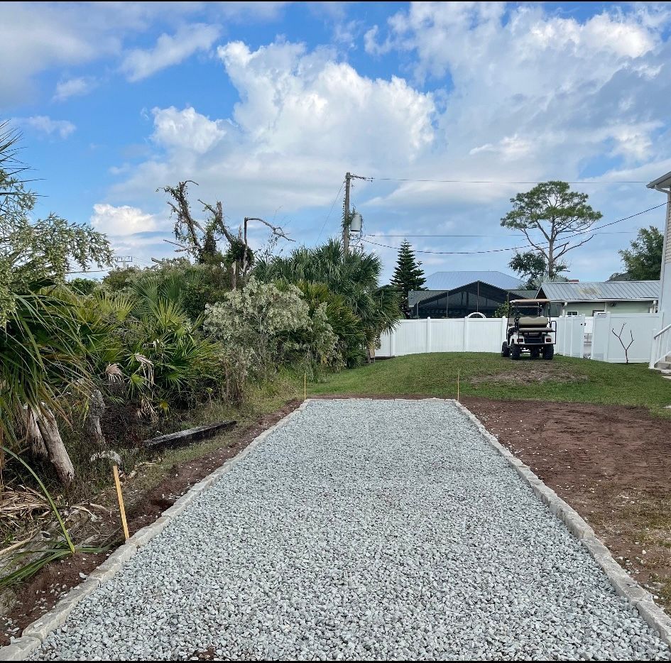 A gravel driveway leading to a house with a golf cart parked on the side.