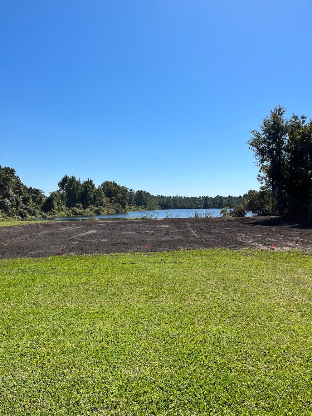 A large grassy field with a lake in the background