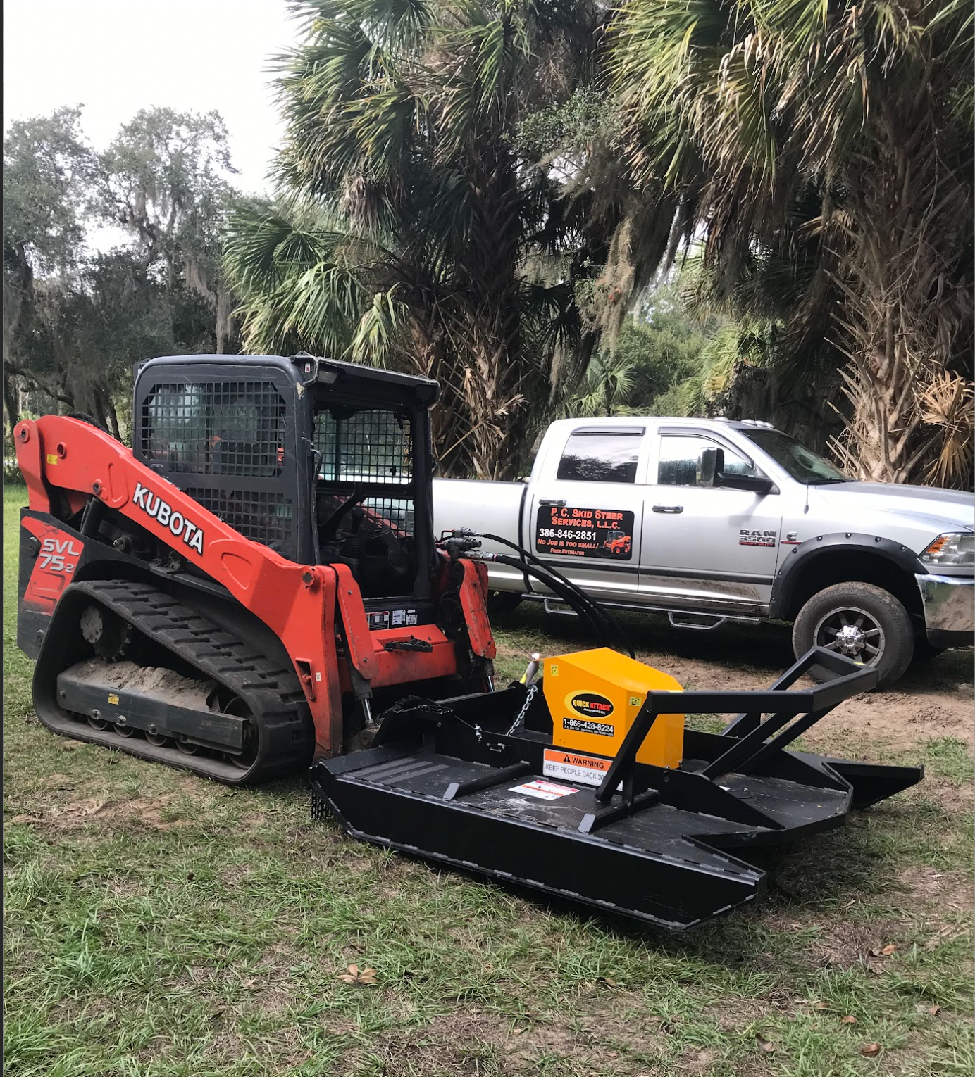 A bulldozer is parked next to a truck in the grass.