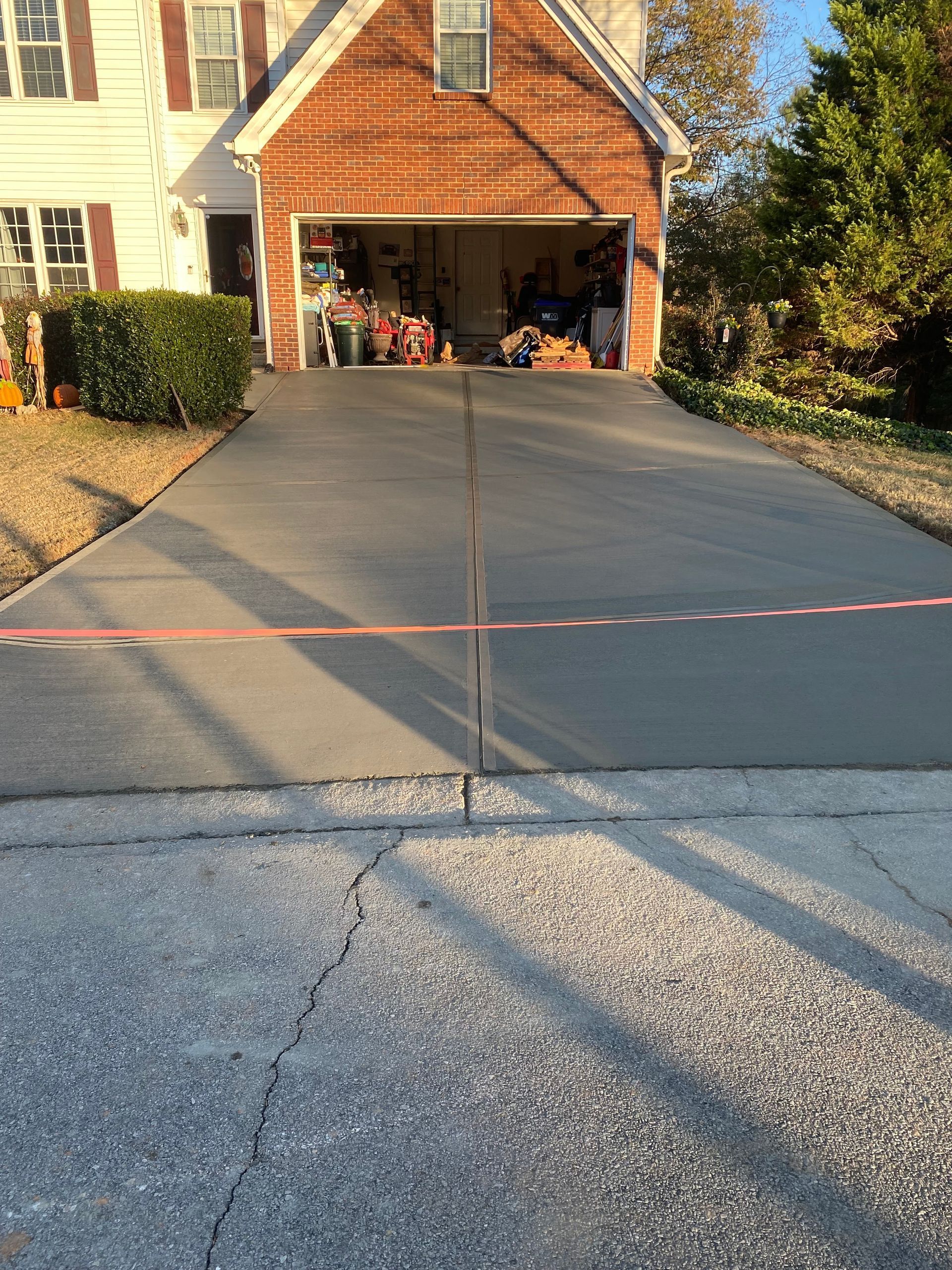 Newly poured gray concrete driveway in front of a house with an open garage.