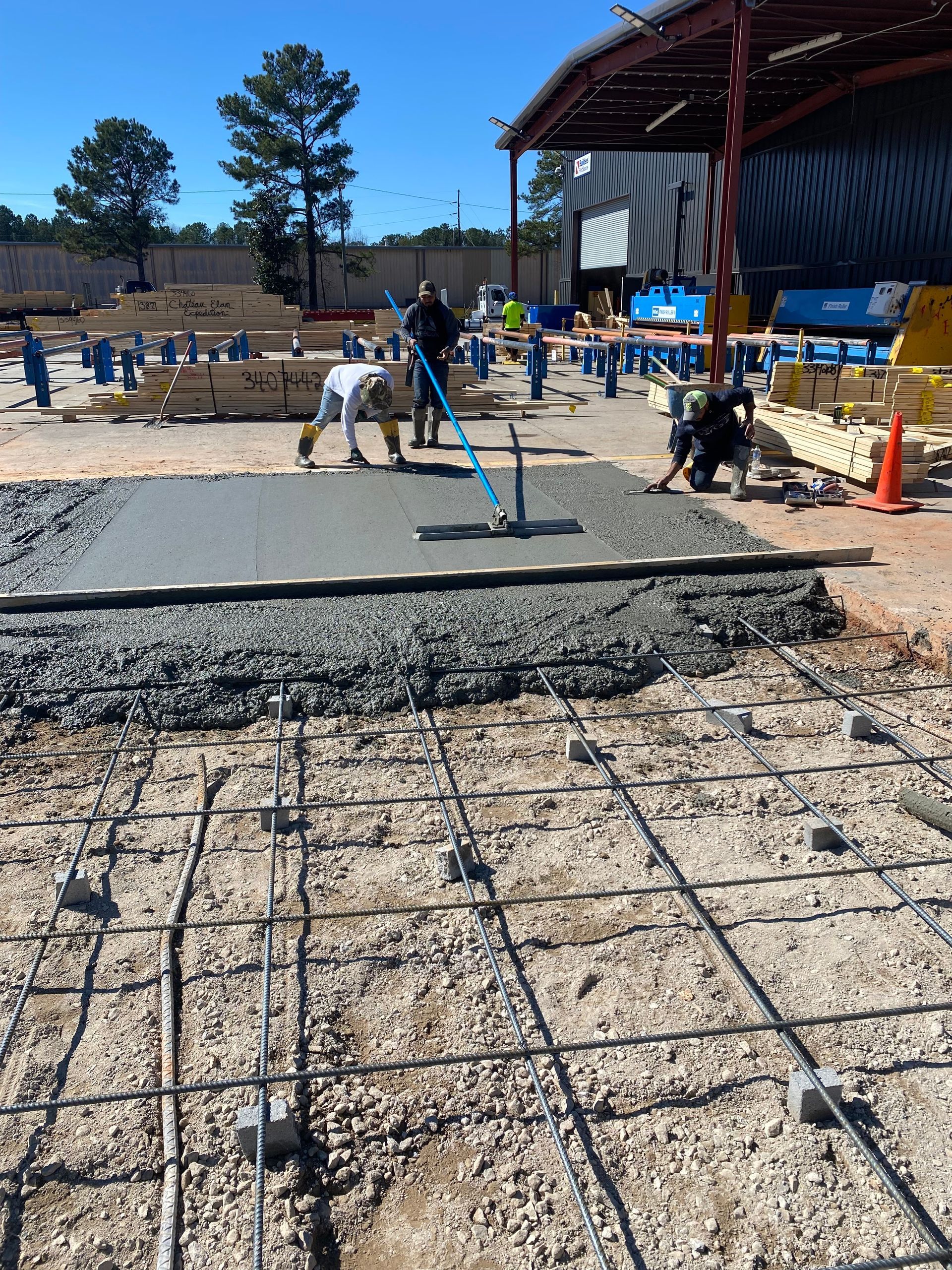 Construction workers pouring concrete over rebar on a construction site.