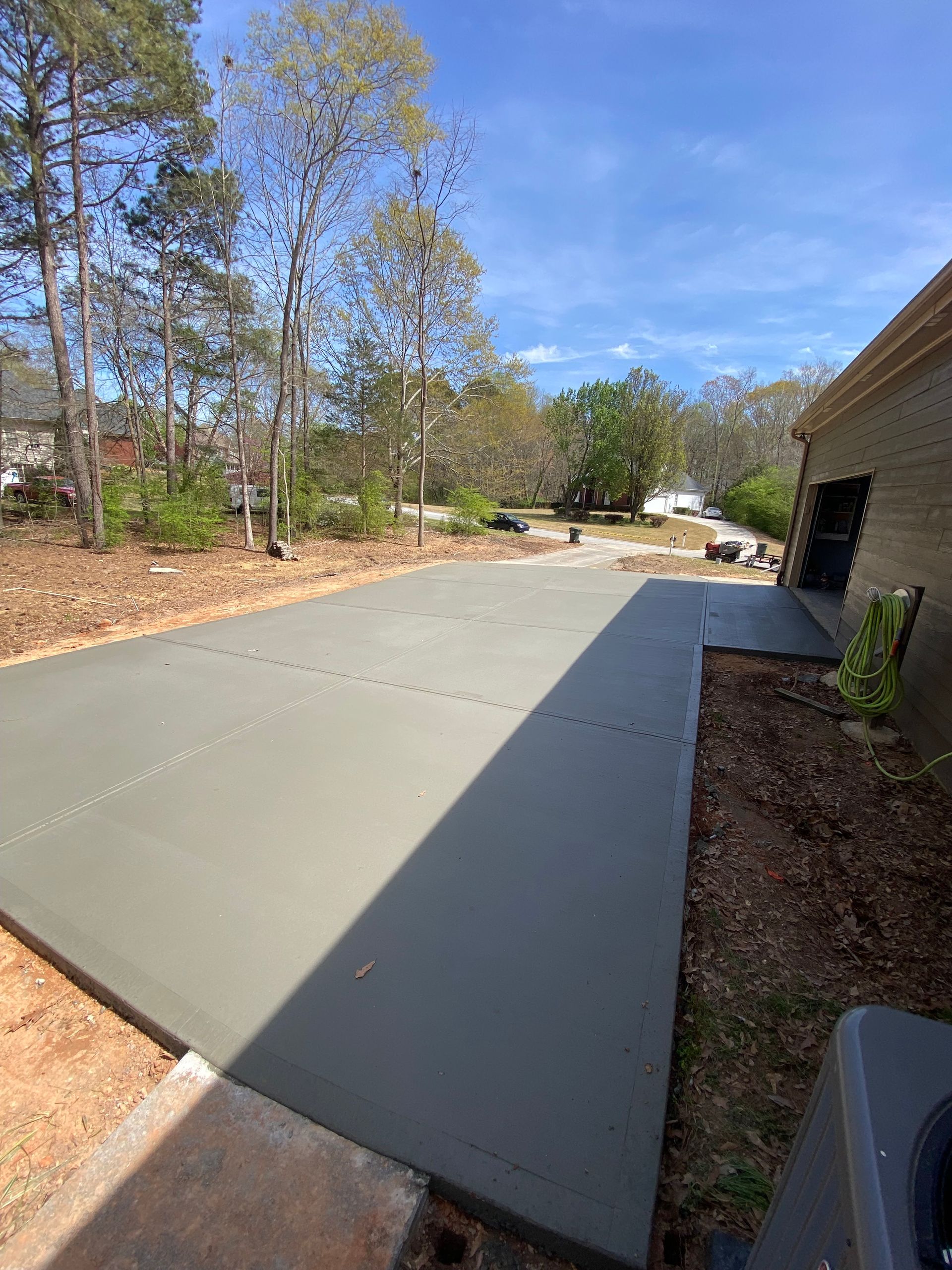 Newly poured concrete driveway next to a brick building, sunny day.
