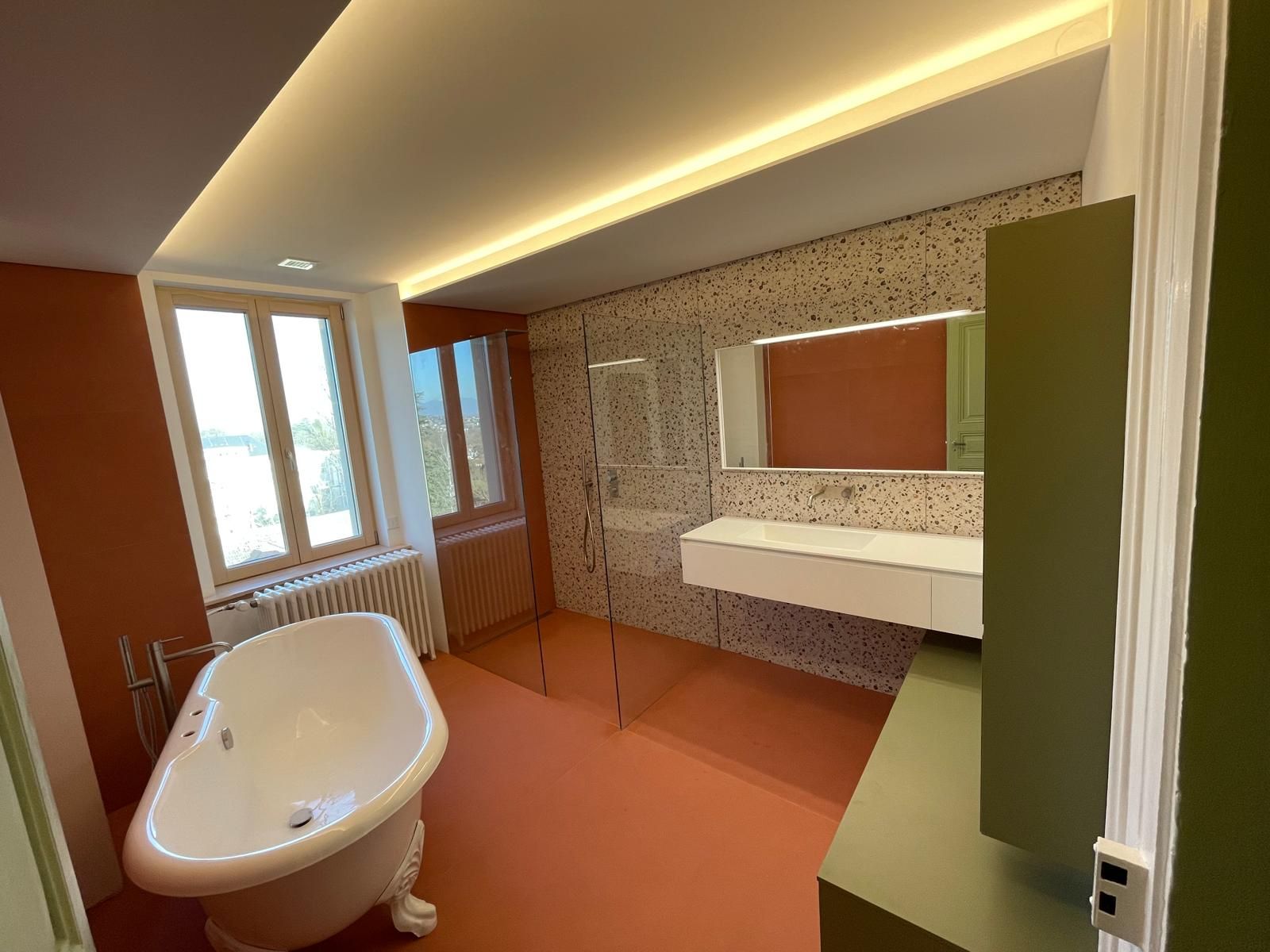 Une salle de bain avec baignoire, lavabo, miroir et fenêtre.