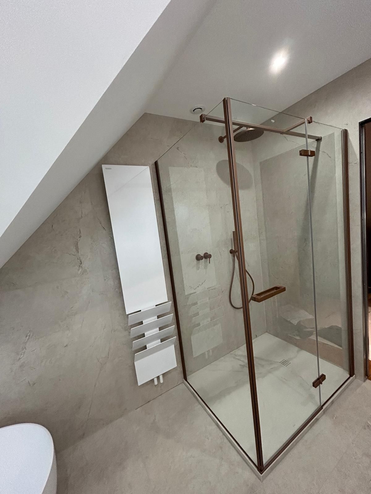 Cabine de douche moderne avec cadre en bronze, dans une salle de bain avec plafond incliné.