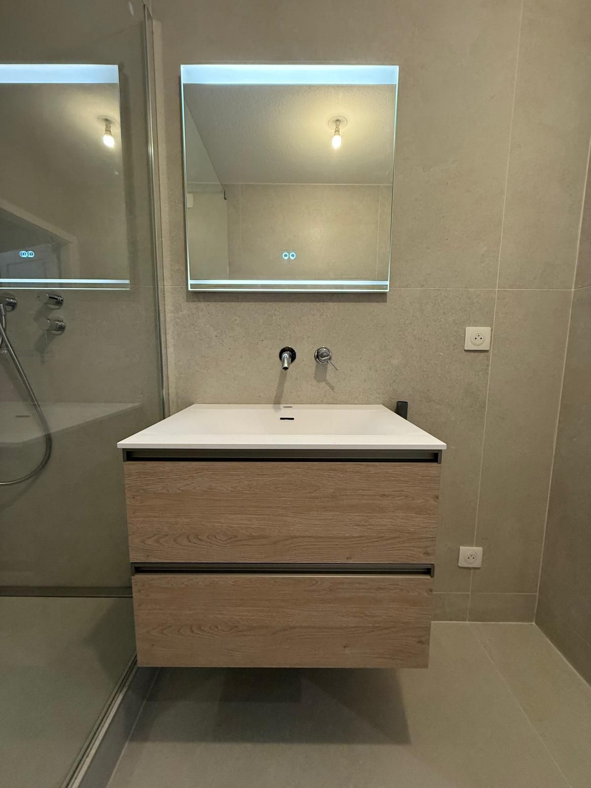 Salle de bain avec vanité flottante en bois, comptoir blanc et miroir carré avec lumière.