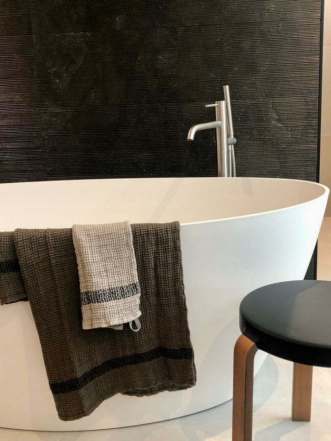 Une salle de bain avec une baignoire et un tabouret
