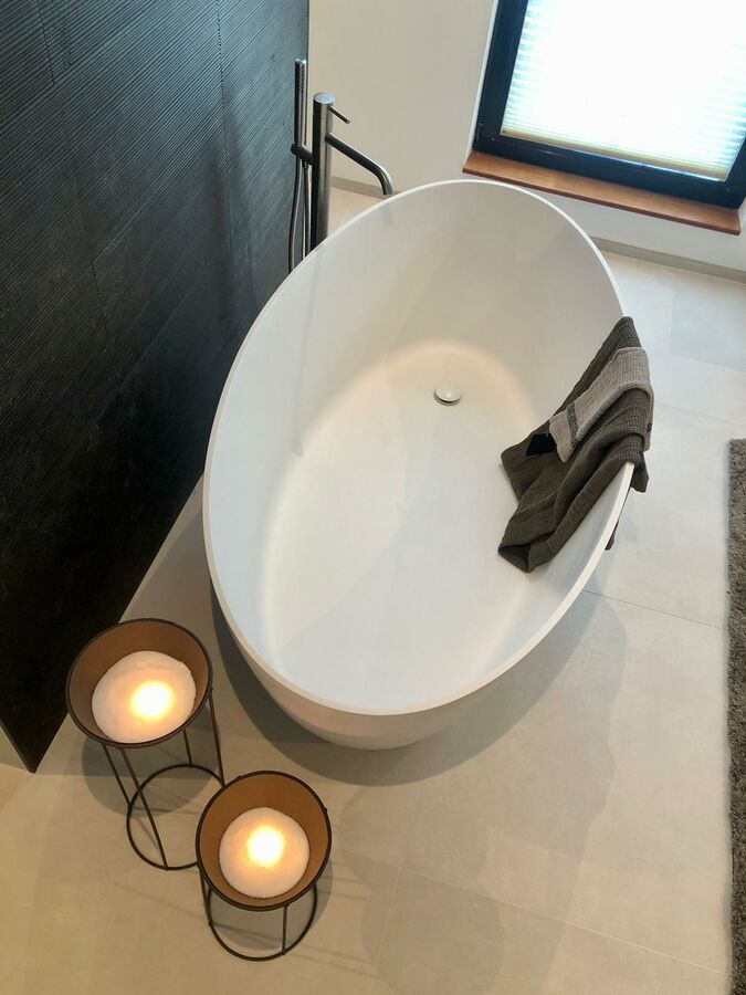 Une salle de bain avec une baignoire et deux bougies au sol