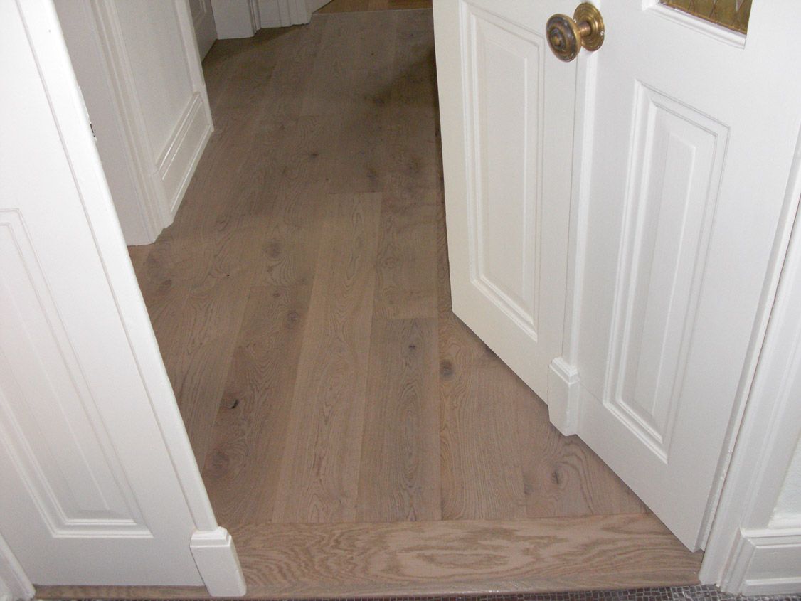 Un couloir avec un plancher en bois et une porte blanche