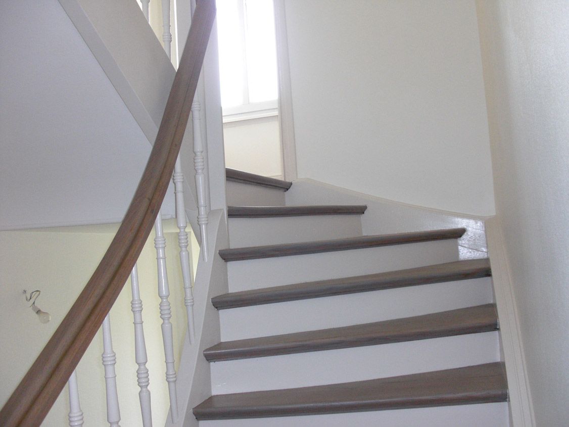 Un escalier en colimaçon avec une rampe en bois et des marches blanches