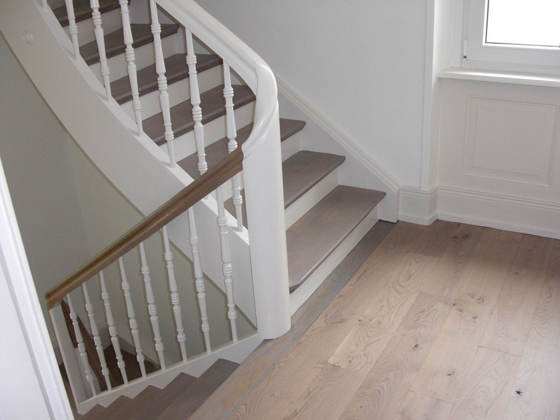 Un escalier avec une rampe blanche et des marches en bois