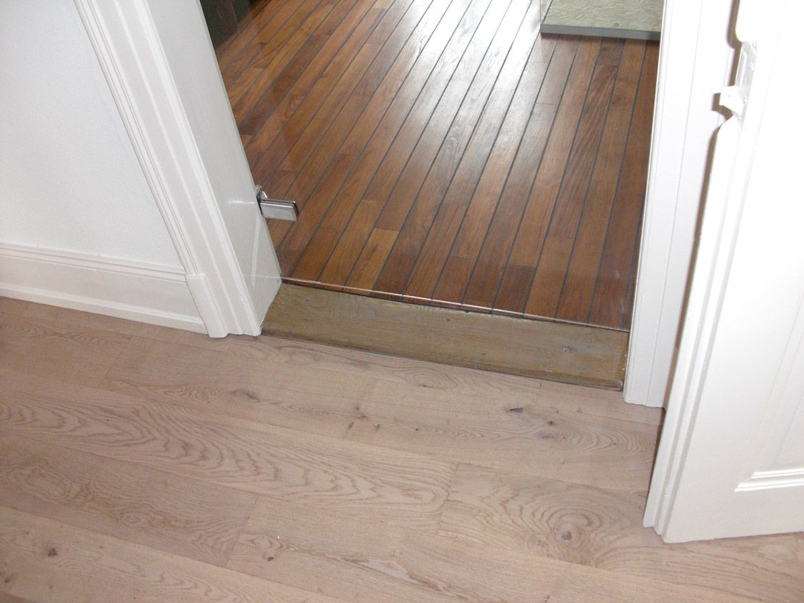 Une porte avec un plancher en bois et un mur blanc