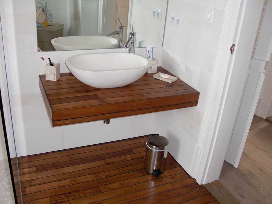 Salle de bain avec plan et sol en bois, lavabo blanc, poubelle en acier inoxydable.