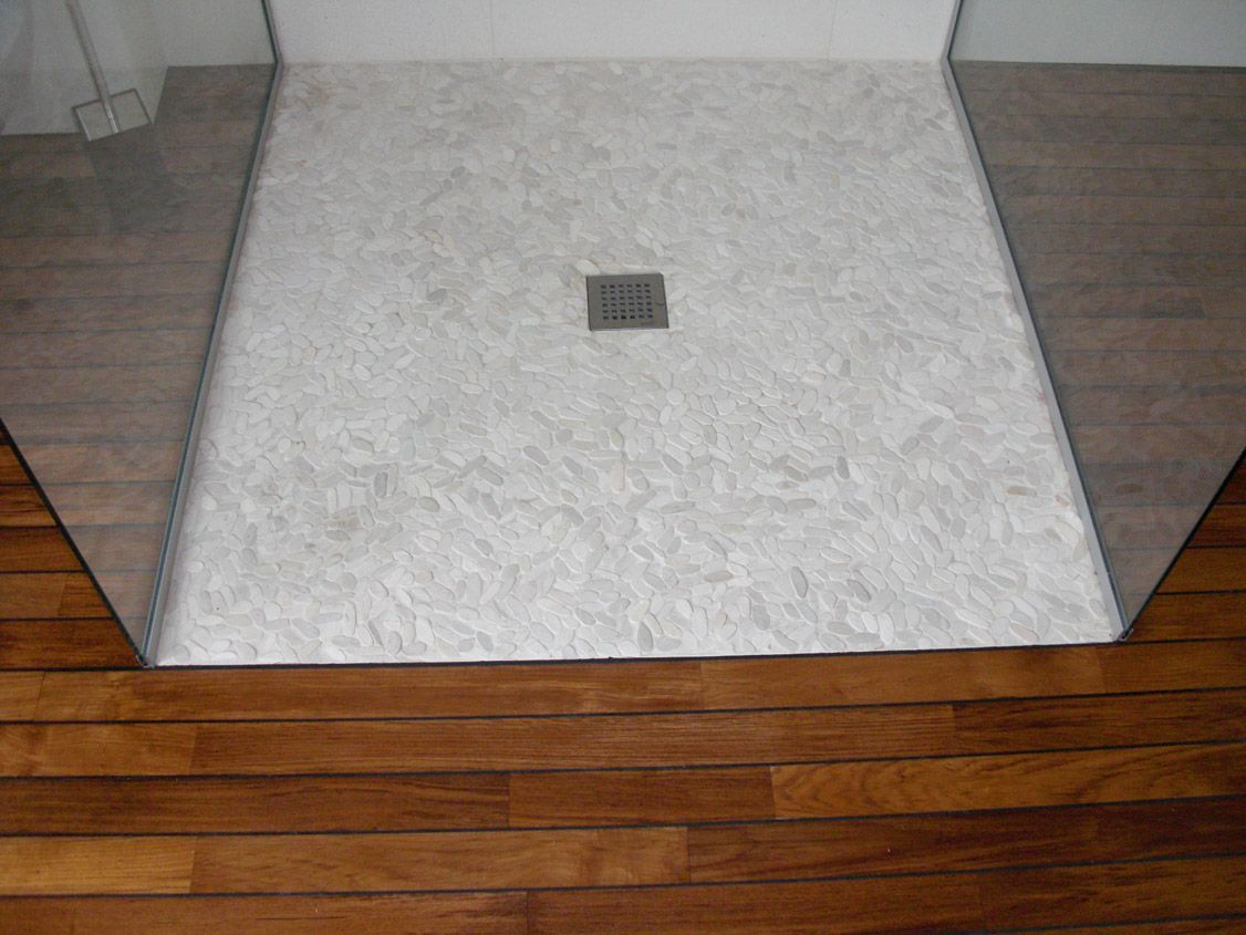 Une cabine de douche avec un plancher en bois dans une salle de bain.