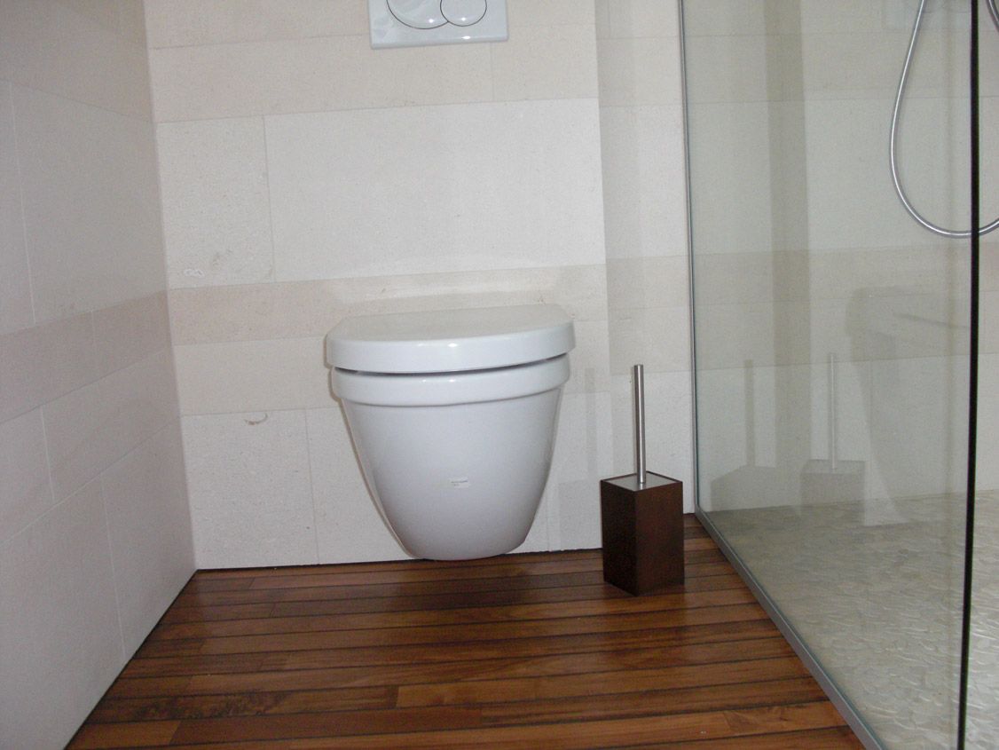 Une salle de bain avec des toilettes et une brosse au sol