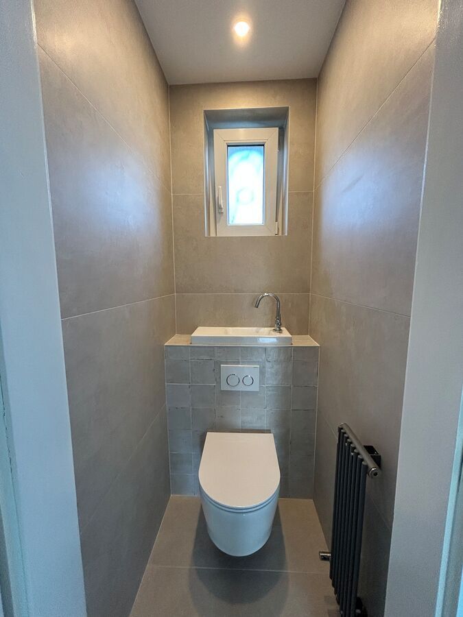 Une petite salle de bain avec WC, lavabo et fenêtre.