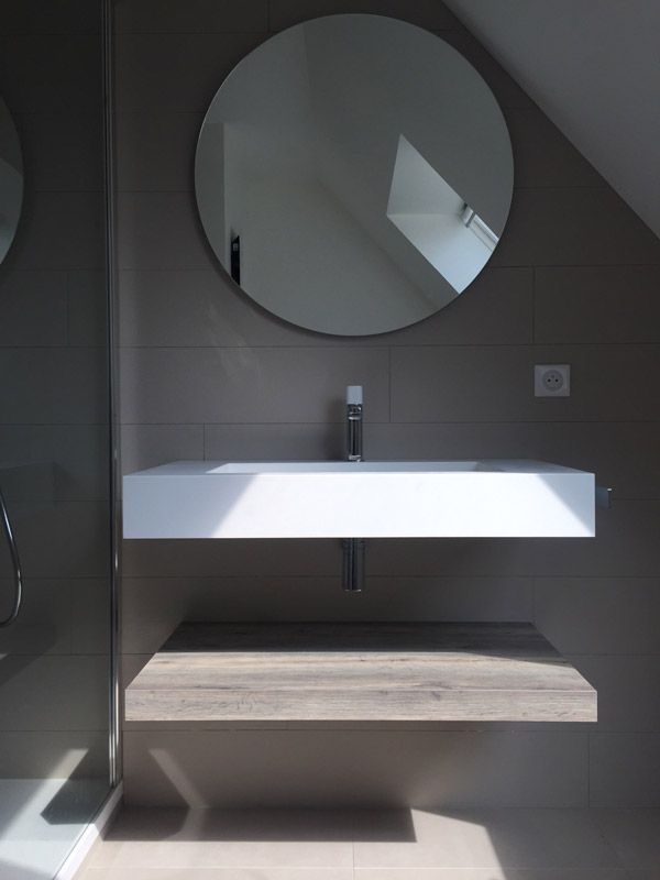 Une salle de bain avec un lavabo et un miroir rond au mur.