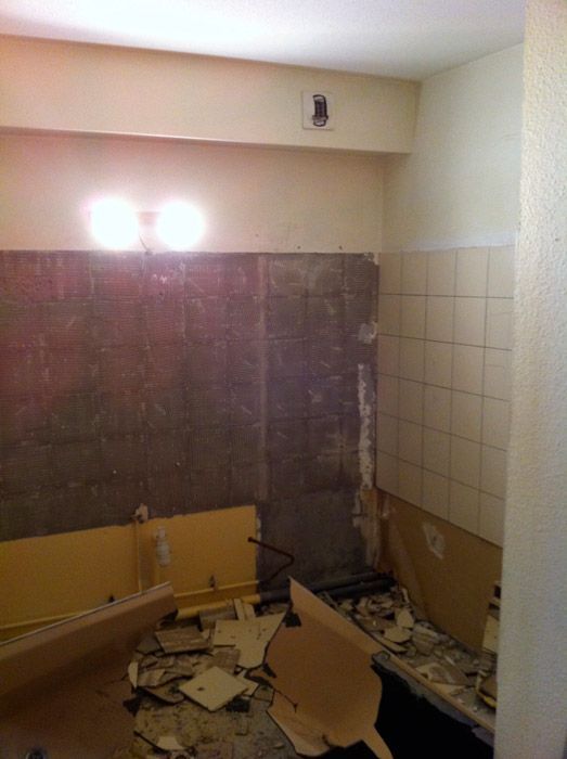 Une salle de bain est en cours de rénovation et il y a beaucoup de déchets sur le sol.