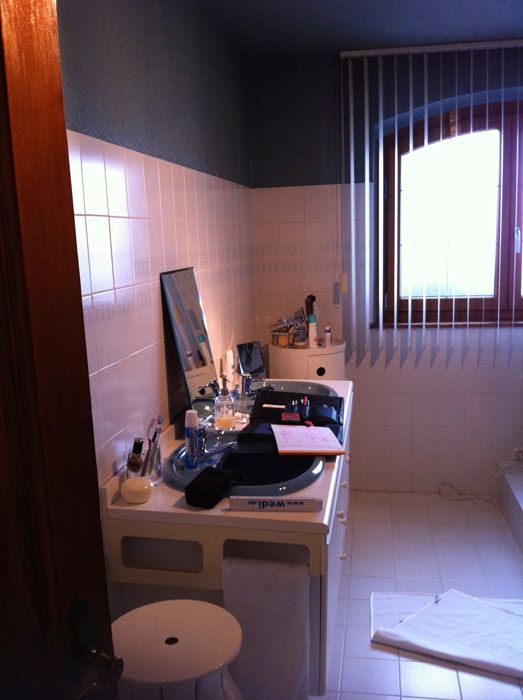 Une salle de bain avec un lavabo et une fenêtre avec des stores