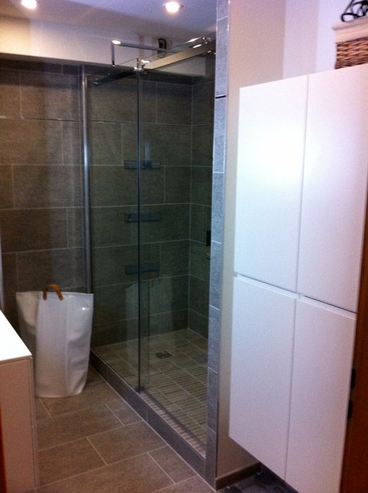 Une salle de bain avec une douche à l'italienne et un panier à linge