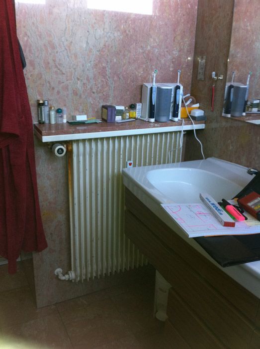 Une salle de bain avec un lavabo, un radiateur et un miroir
