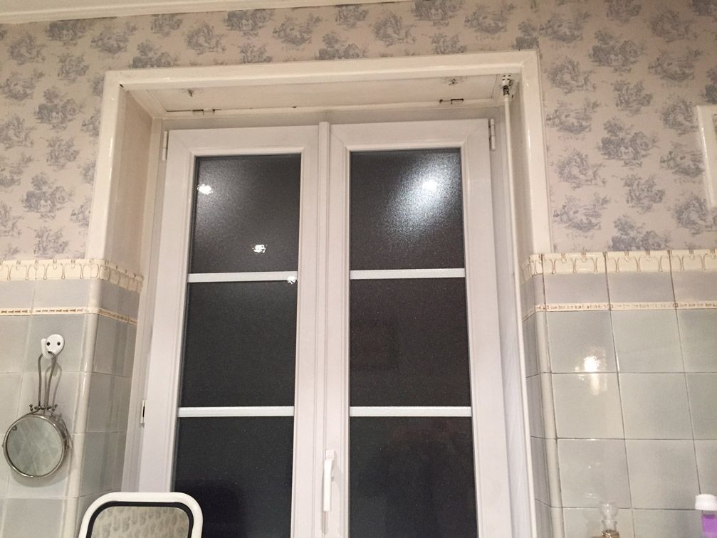 Une salle de bain avec une fenêtre blanche et un miroir.