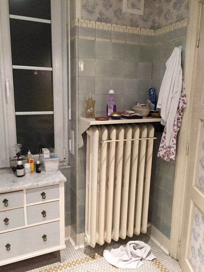 Une salle de bain avec radiateur, commode et fenêtre.