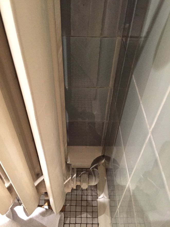 Un rideau de douche est suspendu sur un sol carrelé dans une salle de bain.