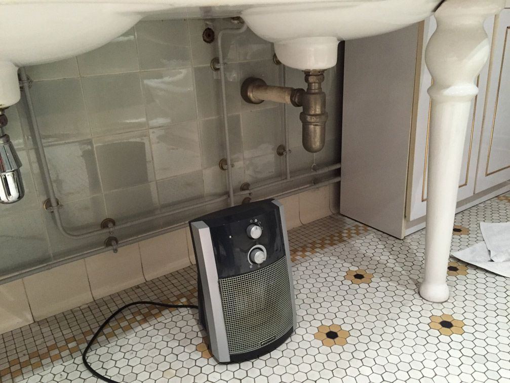Un ventilateur est placé sous un lavabo dans une salle de bain.