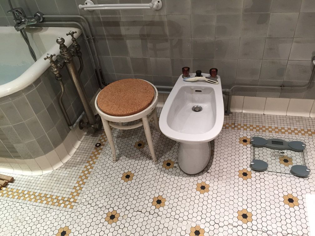 Une salle de bain avec bidet, tabouret, pèse-personne et baignoire.