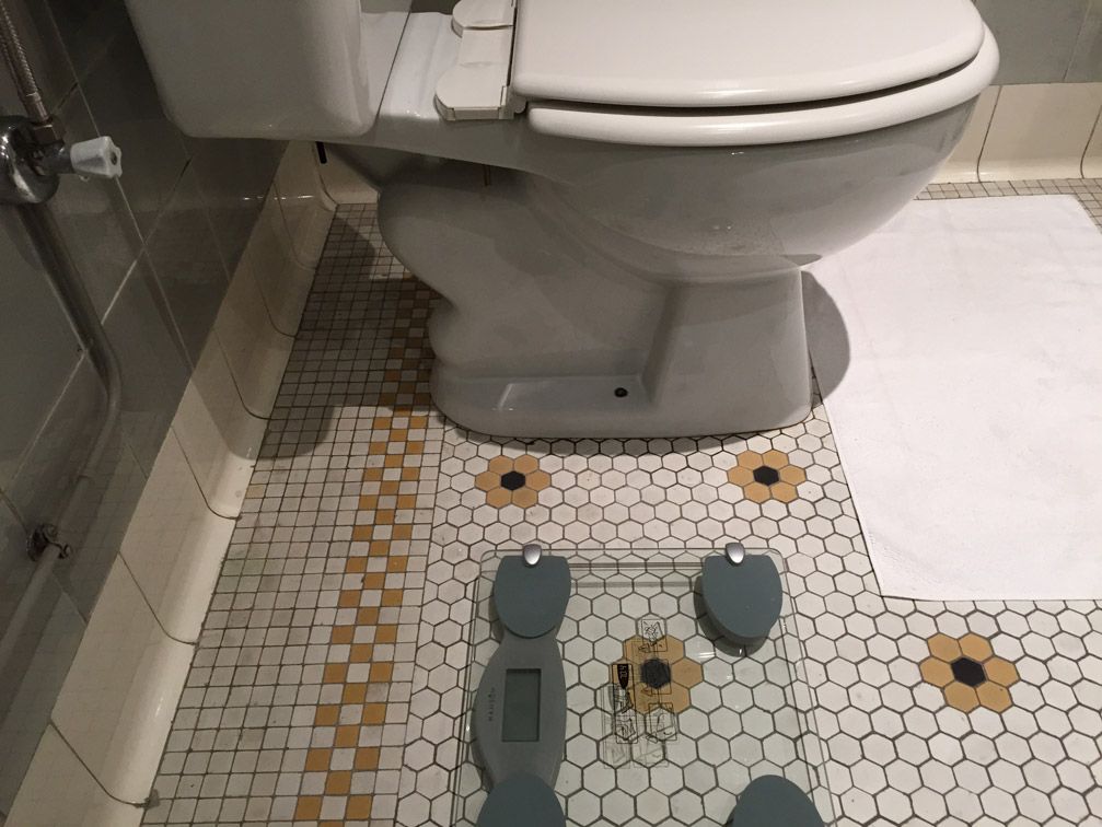 Une salle de bain avec toilettes et une balance au sol