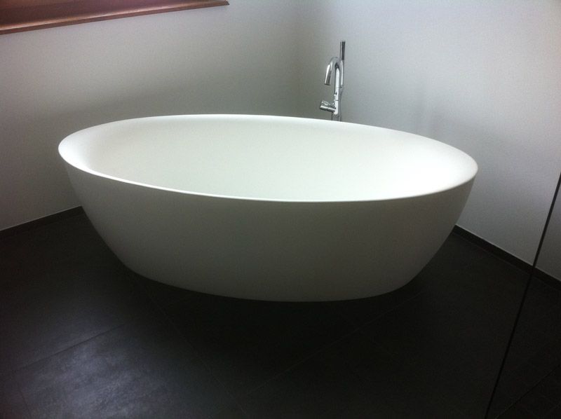 Une baignoire blanche est posée sur un sol noir dans une salle de bain