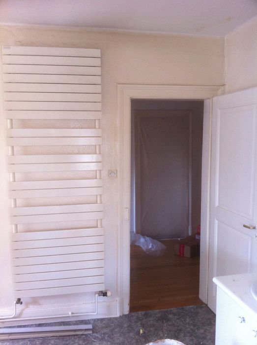 Une salle de bain avec un grand radiateur blanc au mur
