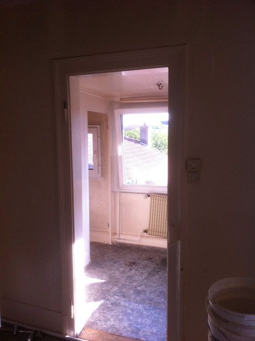 Une pièce avec une fenêtre et un seau sur le sol