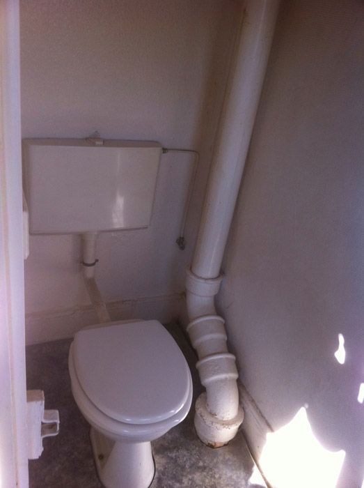 Une salle de bain avec des toilettes et un tuyau qui en sort