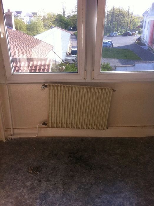 Une pièce vide avec un radiateur et une fenêtre.