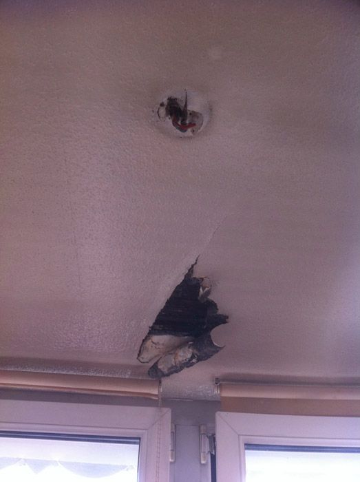 Un plafond avec un trou et une fenêtre en arrière-plan.