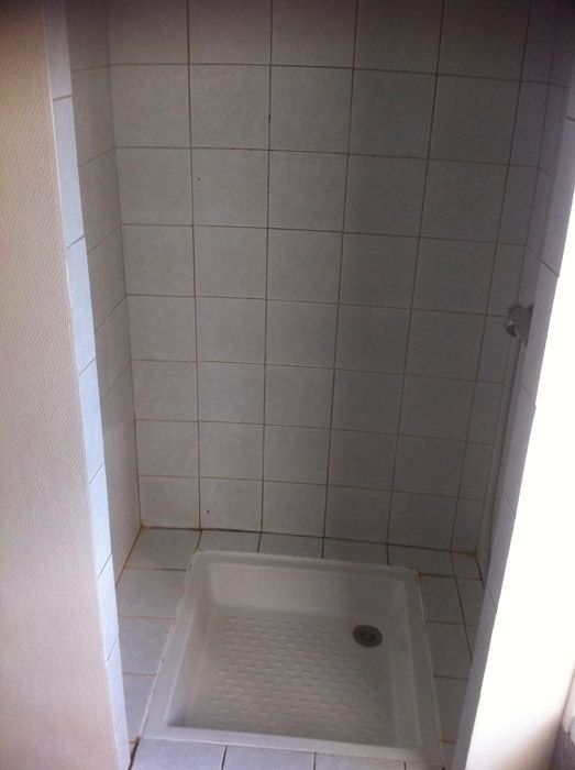 Une salle de bain avec du carrelage blanc et une cabine de douche